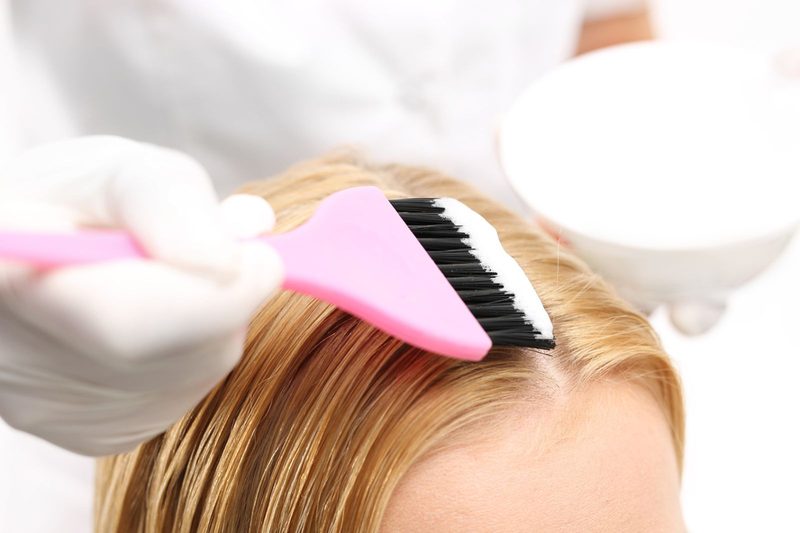 Friseurin trägt Haarfarbe mit dem Pinsel auf