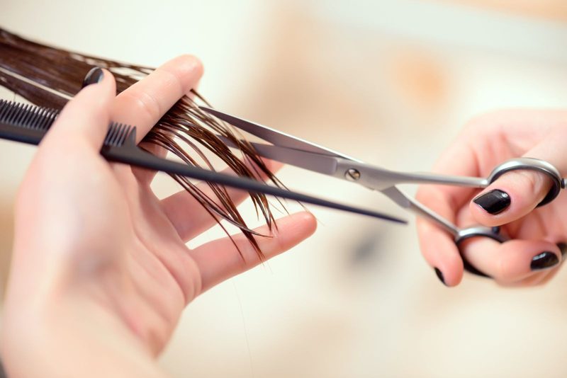 Friseurin schneidet Haarspitzen mit Schere und Kamm