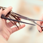 Getting rid of those split ends. Cropped shot of a female hairdresser cutting clients hair with scissors at beauty salon